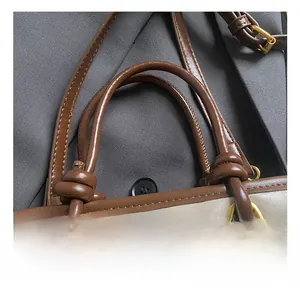 Close-up of leather handbag handle with knotted design and golden metal ring detail