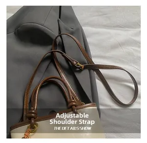 Detail of adjustable shoulder strap with vintage gold hardware on two-tone bucket bag