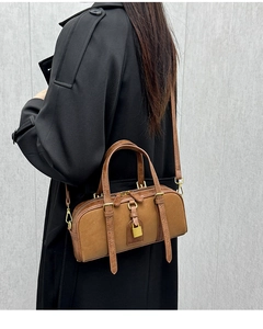 Close-up of a vintage brown leather Boston bag with gold padlock and slim shoulder strap