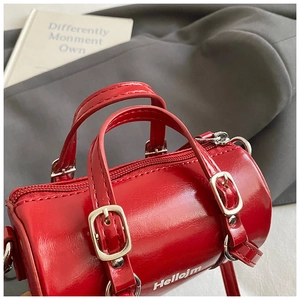 Detalle de bolso Boston rojo en cuero brillante con herrajes plateados y asas superiores