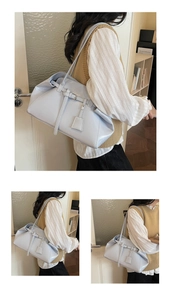Detail view of light blue glossy leather underarm bag with decorative belt and tag