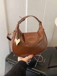 Borsa a mezzaluna marrone lucida con manico intrecciato e ciondolo a cuore dorato da donna