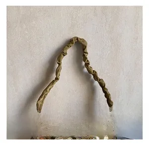 Close-up of a ruffled fabric handle and sparkling gold sequins on a trendy shoulder bag