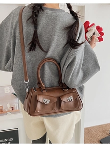 Close-up of brown faux leather boston bag with silver Gancini buckles and front pockets