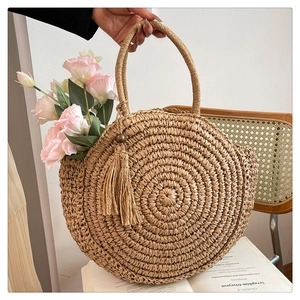 Detail of round straw bag with natural woven texture and hanging tassel with wooden beads