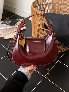 Borsa a mezzaluna in vernice bordeaux con ciondolo a cuore dorato e tracolla inclusa