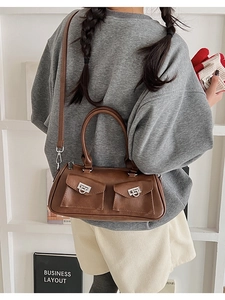 Close-up of brown faux leather Boston bag featuring dual front pockets and silver hardware