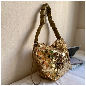 Macro shot of large golden sequins texture and contrasting pleated cloud shoulder strap