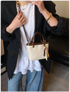 Detail of cream crossbody bag with brown handle, colorful beads and fashion lettering