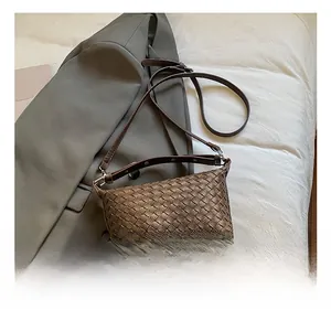 Detail shot of brown hand-woven leather texture and metallic strap hardware on bag