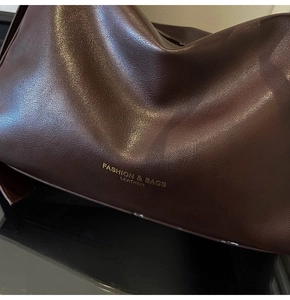 Close-up detail of dark brown litchi pattern leather and gold FASHION & BAGS logo