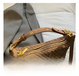 Detailed view of brown woven shoulder bag with gold zipper and matte finish texture