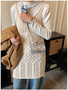 Detalle de un mini bolso cilíndrico plateado con acabado metálico y asas dobles elegantes
