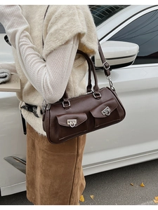 Detail of dark brown leather Boston bag with double front pockets and silver buckles