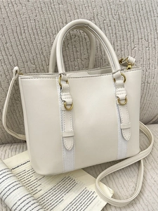 Chic beige bucket bag with gold hardware and top handles shown in a lifestyle setting