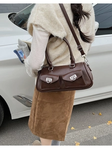 Macro view of dark brown leather Boston bag with silver buckles and multi-pocket design