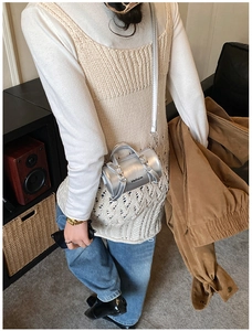 Bolso mini cilíndrico plateado con asa y letras Hellojm mostrado por modelo en interiores