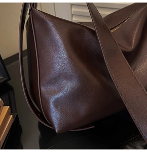 Detail of a large brown leather tote showing smooth texture and high-quality stitching