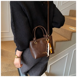 Detail view of dark brown retro crossbody bag with colorful bead fringe on stairs
