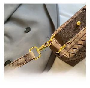 Close-up of golden metal hooks on brown woven leather bag with professional gray suit background