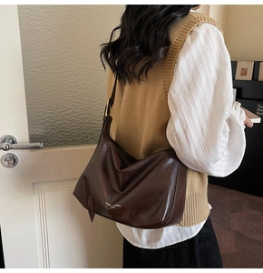 Detail view of large dark brown hobo bag with wide shoulder strap and white logo