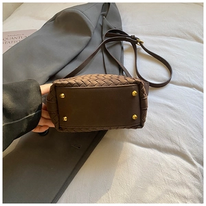 Close-up of deep brown woven bag bottom featuring four golden protective metal studs