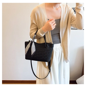Chic black quilted tote bag with a houndstooth scarf on model in a soft minimalist interior