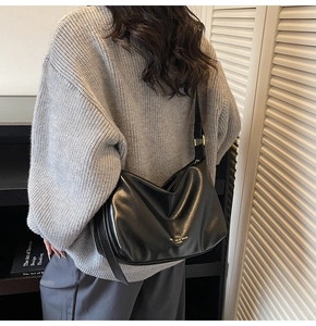 Detail of a black leather hobo bag featuring gold fashion lettering for autumn style