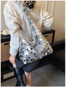 Detailed close-up of a silver sequin tote bag with a reflective finish and ruched strap