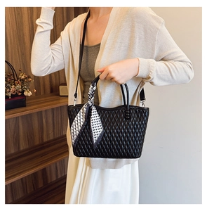 Detail of black quilted tote bag with diamond pattern and houndstooth scarf on model
