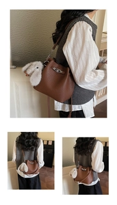 Close-up of brown litchi grain leather bucket bag with silver lock and plush bunny charm