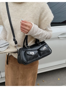 Detail of black Boston bag with dual front pockets and silver buckles on a crossbody strap