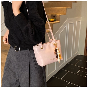 Pink leather handbag with double handles and a vintage colorful beaded charm detail