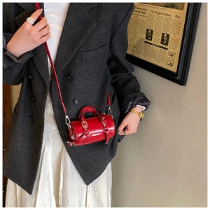 Detalle del mini bolso cilíndrico rojo con texto Helloim y hebilla metálica dorada