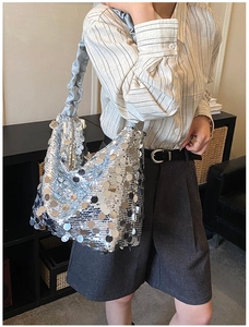 Silver sequin shoulder bag with blue ruffled strap worn by model in a stylish setting