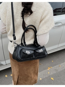 Detail of a black leather bowling bag with silver horseshoe buckles in an outdoor setting