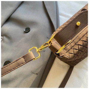 Close-up of deep brown woven leather bag with premium gold rotating metal buckle detail