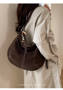 Détail du sac hobo marron foncé avec surpiqûres et gland à perles sur le côté