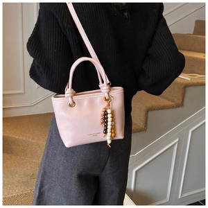 Detailed shot of pink leather bucket bag with bead tassel and gold hardware accents
