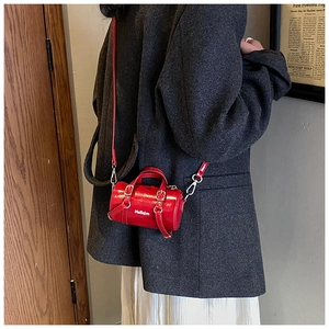 Detalle del mini bolso cilindro rojo con logo Hellojm y correa ajustable en un modelo