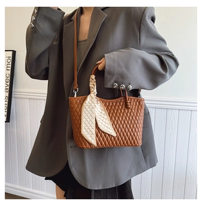 Detail of brown quilted handbag with decorative silk scarf handle in elegant setting