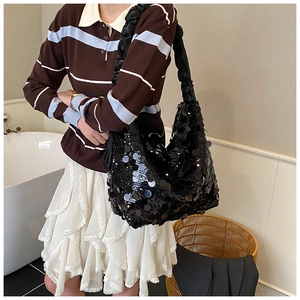 Close-up of black sequined tote bag with pleated handle shown on a model for party styling