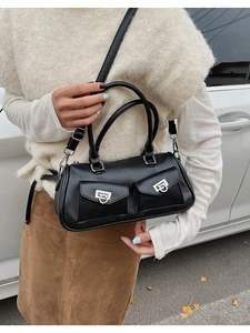 Outdoor street view of a black PU leather Boston bag with double pockets and metal rings