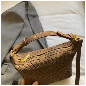Detail of brown woven leather texture with gold zipper and stud hardware on handbag
