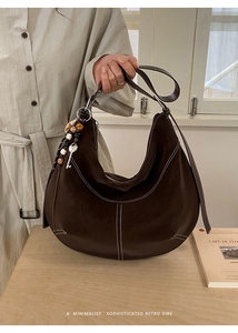Détail du sac hobo marron mat avec coutures blanches et breloque en perles colorées