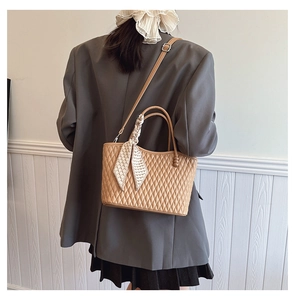 Detail of khaki quilted handbag with geometric silk scarf and adjustable leather strap