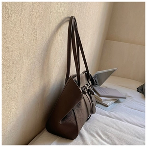 Detail of dark brown pebble leather tote bag featuring unique knotted double shoulder straps