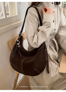 Détail du sac hobo marron foncé avec coutures blanches et breloque à pompon