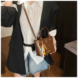 Detail view of brown vintage bucket bag with beaded tassel and adjustable strap
