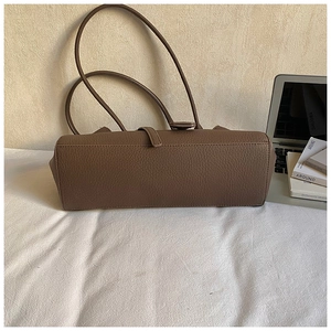 Detail showing the bottom structure and stitching of a dark brown litchi grain leather bag